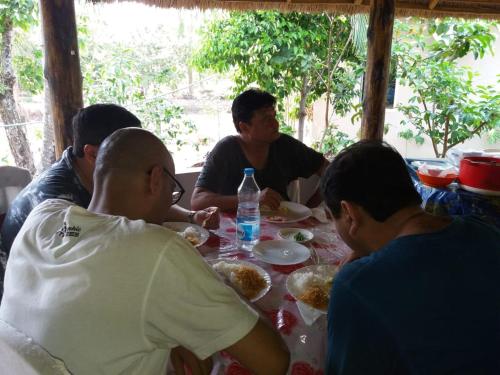 a group of people sitting around a table eating food at Solitary Nook in Gosāba