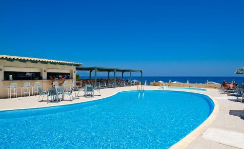 a swimming pool with chairs and the ocean in the background at Lissos Beach in Plataniás