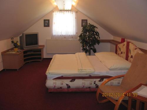 a attic room with two beds and a television at Šindlerův Dvůr in Krmelín