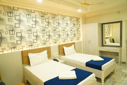 a room with two beds and a wall with photographs at Hotel Swagath Grand Miryalaguda in Miriālgūda
