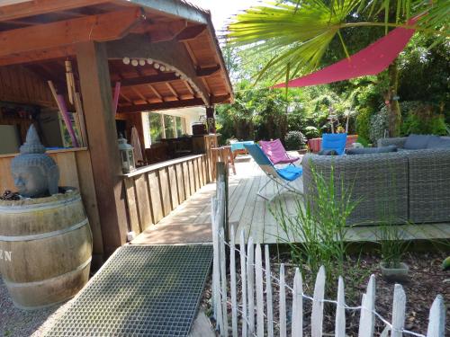 a wooden porch with a barrel and chairs and an umbrella at Villa piscine chauffée & spa sur le Bassin d Arcachon - proche plage et océan in Lanton