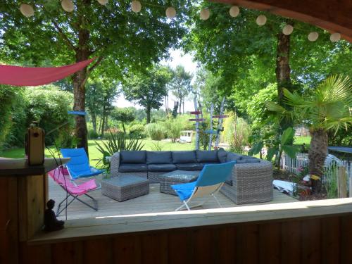 a patio with a blue couch and chairs and trees at Villa piscine chauffée & spa sur le Bassin d Arcachon - proche plage et océan in Lanton