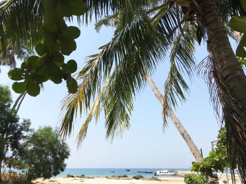 a view of the beach from under two palm trees at Nhi Lo Home Stay in Tân Hiệp