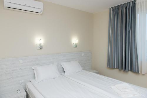 a white bed with two pillows and a window at Hiora Apartments Vasiliko in Tsarevo