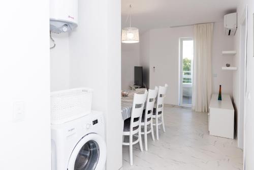 a white laundry room with a table and chairs at Hiora Apartments Vasiliko in Tsarevo