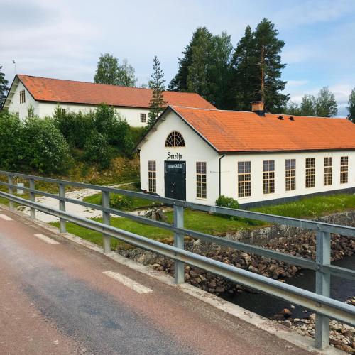 a white building with an orange roof next to a road at Furudals Bruk in Furudals Bruk