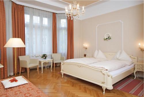 ein Schlafzimmer mit einem großen weißen Bett sowie einem Tisch und Stühlen in der Unterkunft Hotel Pension Baronesse in Wien