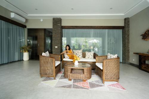a woman sitting on a couch in a living room at Del Cielo Villa Jimbaran in Jimbaran