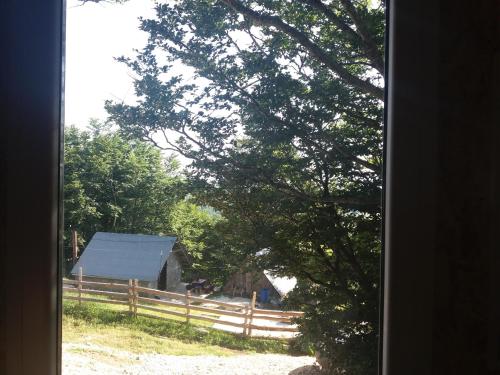 a window view of a fence and a barn at Katun Ljeljenak in Pluzine