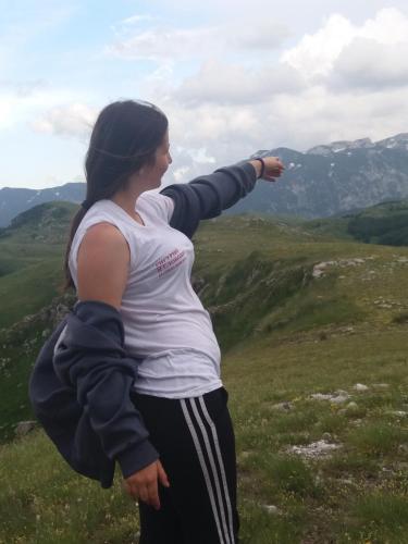 a woman standing on a hill with her arm outstretched at Katun Ljeljenak in Pluzine