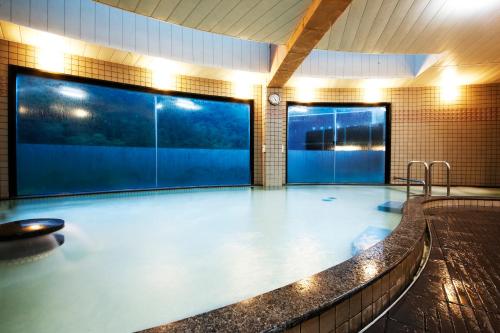a swimming pool in a building with a large aquarium at Blue Villa Anabuki in Mima