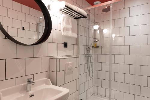 a white tiled bathroom with a sink and a mirror at H&ocirc;tel Bristol Reims in Reims