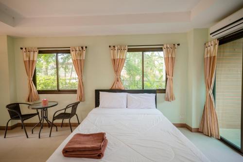 a bedroom with a bed and a table and windows at Banlanna Hotel Lampang in Lampang