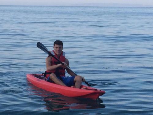 a man sitting on a red kayak in the water at Alexandraki Rooms in Poulithra