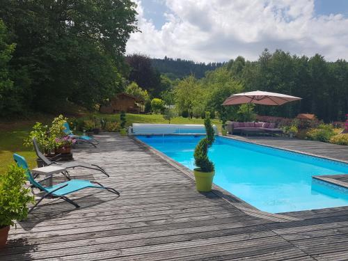 - une piscine avec des chaises et un parasol sur une terrasse en bois dans l'établissement Le Clos des Aulnes, à Anould