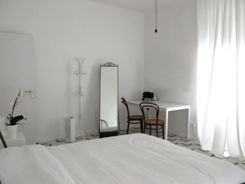 a white bedroom with a bed and a table and chairs at Il Capitano in Lerici