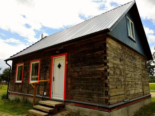 Cabaña de madera pequeña con puerta roja en Dobry Dom, en Sejny