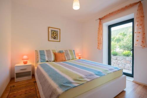 - une chambre avec un lit et une grande fenêtre dans l'établissement Stone Villa Rafael, à Slivno