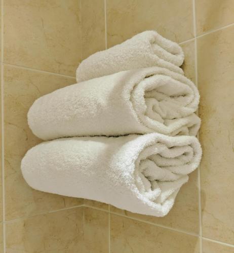 a pile of white towels on a wall in a bathroom at London Beach Country Hotel & Golf Club in Tenterden