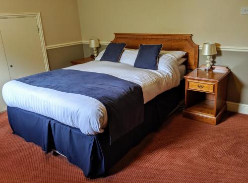 um quarto com uma cama grande com lençóis azuis e brancos em London Beach Country Hotel & Golf Club em Tenterden