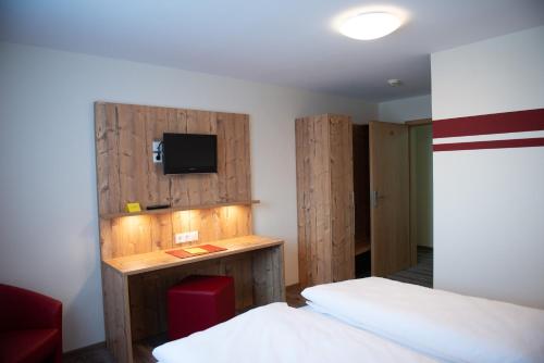 a bedroom with two beds and a tv on the wall at Gasthaus Stroh in Buchholz