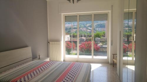 ein Schlafzimmer mit einem Bett und einem großen Fenster in der Unterkunft Appartamento Piave in Praia a Mare