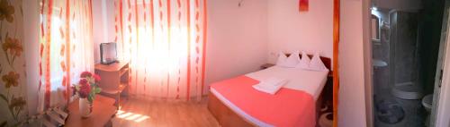 a small bedroom with a red and white bed at Casa Nelu Pescaru in Mahmudia