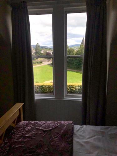 a bedroom with a window with a view of a golf course at Lynburn Country Retreat in Biggar