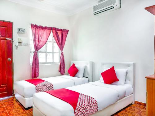 two beds in a room with red and white pillows at D' Anjung Inn in Tangkak