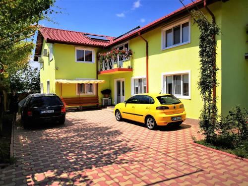 dos autos estacionados frente a una casa amarilla en Casa Nelu Pescaru, en Mahmudia