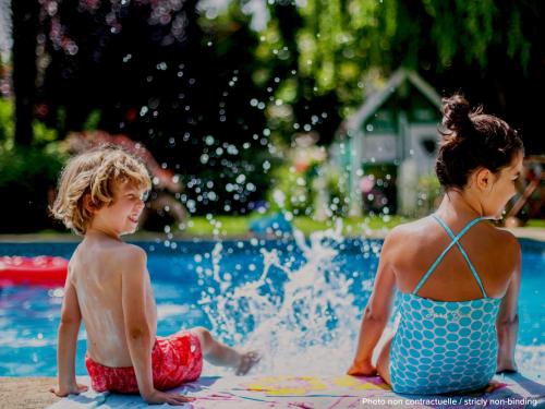 two children sitting in the water at a pool at greet Hotel Beaune in Beaune