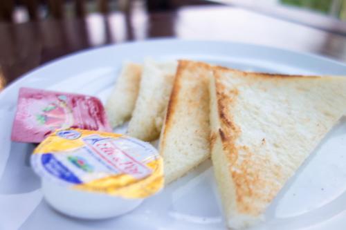 a white plate with two sandwiches and a container of jelly at Kampuak Cottages in Nusa Penida