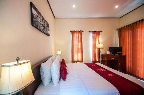 1 dormitorio con 1 cama con almohadas rojas y blancas en Kampuak Cottages en Nusa Penida