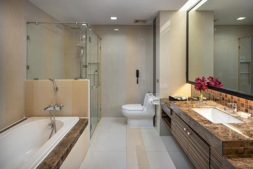 a bathroom with a tub and a toilet and a sink at The Berkeley Hotel Pratunam - SHA Extra Plus in Bangkok