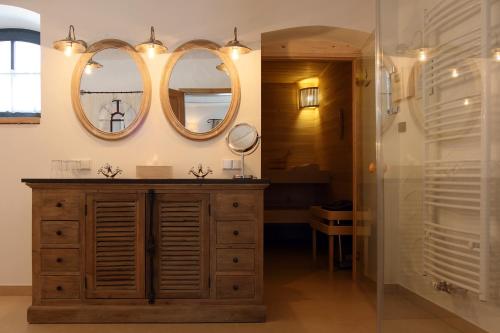 a bathroom with a wooden dresser and two mirrors at Spreewaldresort Seinerzeit in Schlepzig