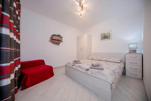 1 dormitorio con 1 cama y 1 silla roja en Apartman Marcela en Rab