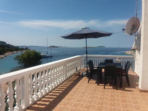 a balcony with a table and an umbrella at Apartments Uvala Murtar in Jezera