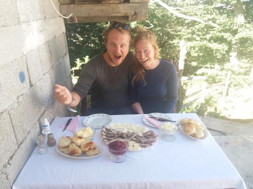 a man and a woman sitting at a table with food at Katun Ljeljenak in Pluzine