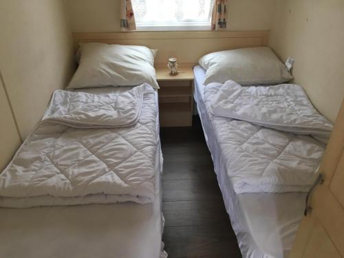 two beds in a small room with a window at Caravanverhuur Zeeland in Wemeldinge