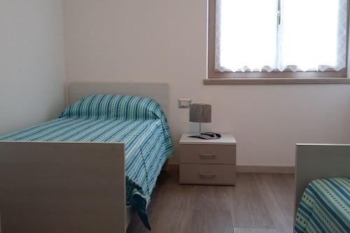 1 dormitorio con 2 camas, mesita de noche y ventana en Chalet La Perla Molveno en Molveno