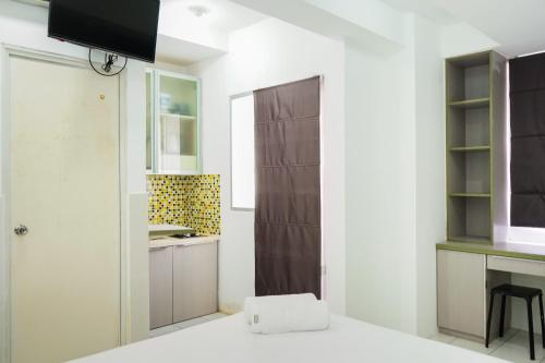 a small kitchen with white walls and a brown door at Spacious Studio Room Menteng Square Apartment By Travelio in Jakarta