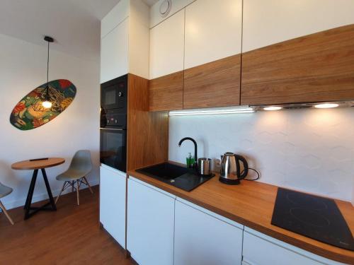 a kitchen with white cabinets and a sink and a table at Prywatne apartamenty w hotelu - 365PAM in Sarbinowo