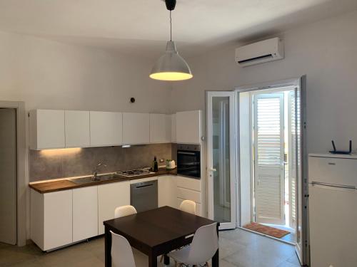 una cocina con armarios blancos y una mesa con sillas. en L'Argonauta en Lampedusa