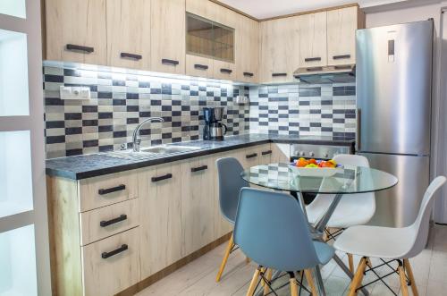 a kitchen with a table and a stainless steel refrigerator at Alley To The Beach in Ierapetra