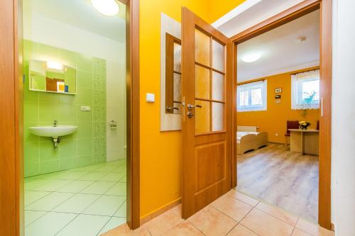 ein Badezimmer mit gelben Wänden, einem Waschbecken und einer Tür in der Unterkunft Hotel & Motorest V Údolí Zlatého potoka in Blšany