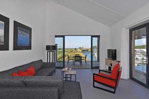 a living room with a couch and a red chair at Appartement voor 4 personen aan d'Ouwe Haven in Kamperland in Kamperland