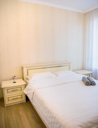 a bedroom with a large white bed and a night stand at Apart Reserve Sloboda Suite in Ivano-Frankivsʼk