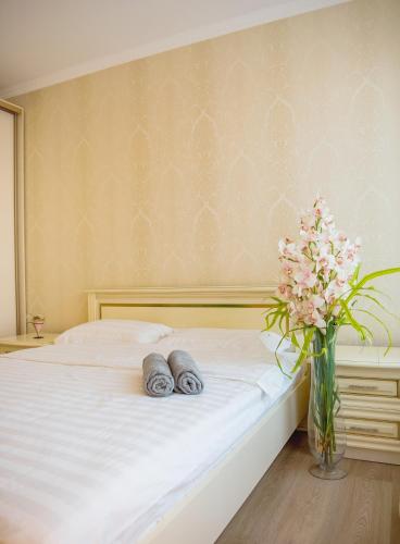 a bed with two towels and a vase of flowers at Apart Reserve Sloboda Suite in Ivano-Frankivsʼk