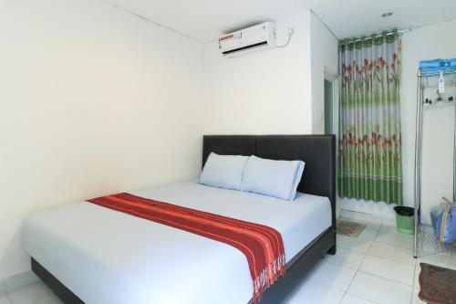 Un dormitorio con una cama blanca con una manta. en Donata House, en Jimbaran
