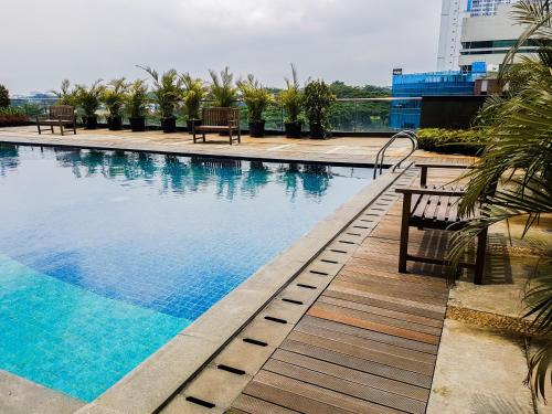 a swimming pool with benches next to a building at Homey Studio Room Tree Park City BSD Apartment near BSD City By Travelio in Tangerang